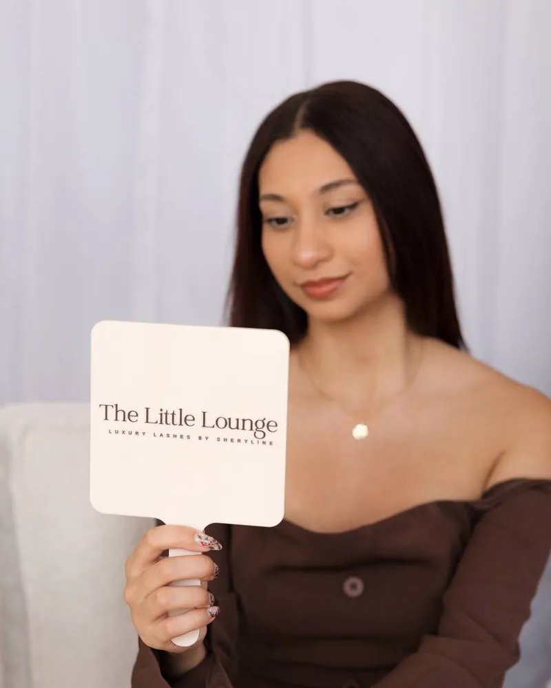 Sheryline holding a hand mirror printed with The Little Lounge logo